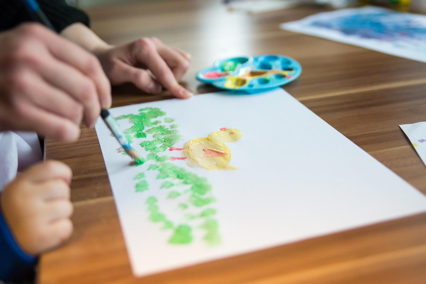 child hands painting with brush